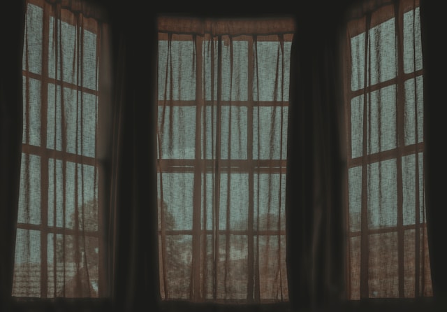 a-dark-room-with-two-open-windows-with-sheer-curtains-